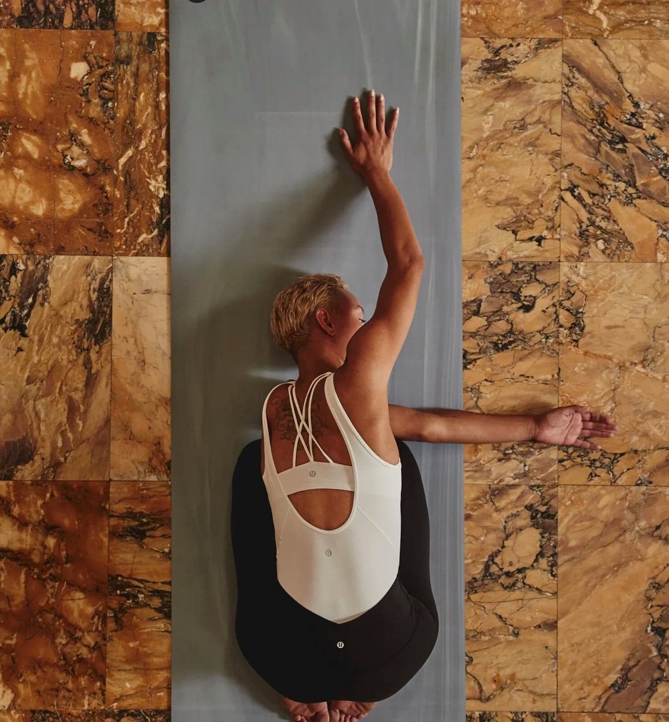 Model stretching against a yoga mat on marble