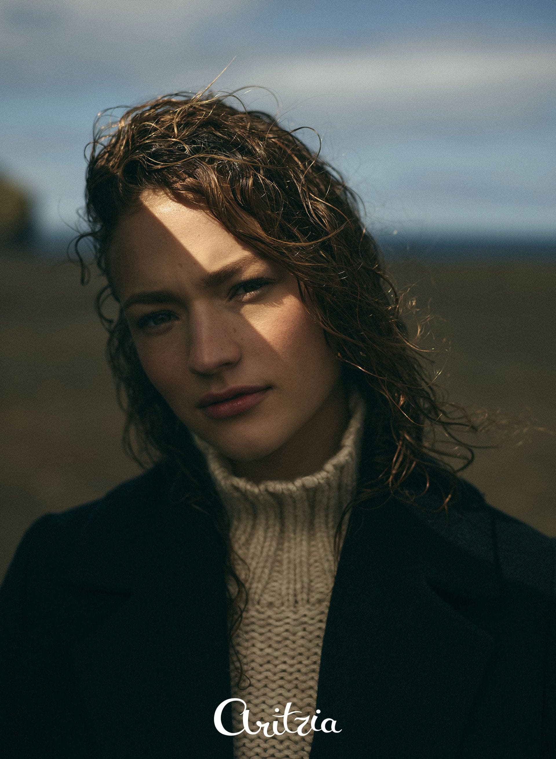 Model in a turtleneck and coat, windswept hair