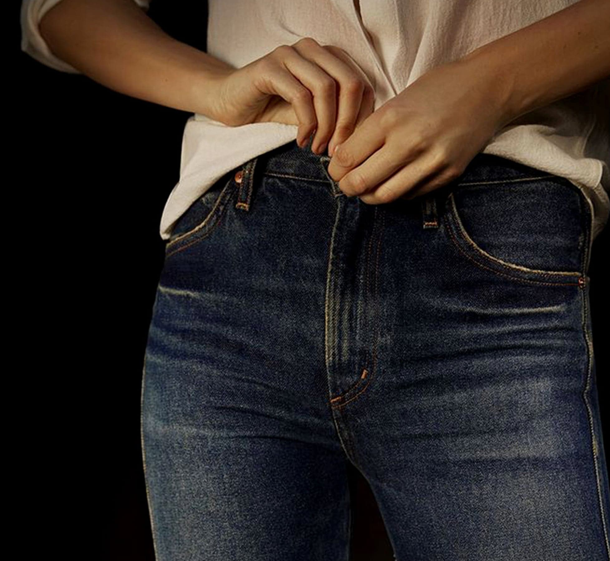 Hands buttoning high-rise jeans
