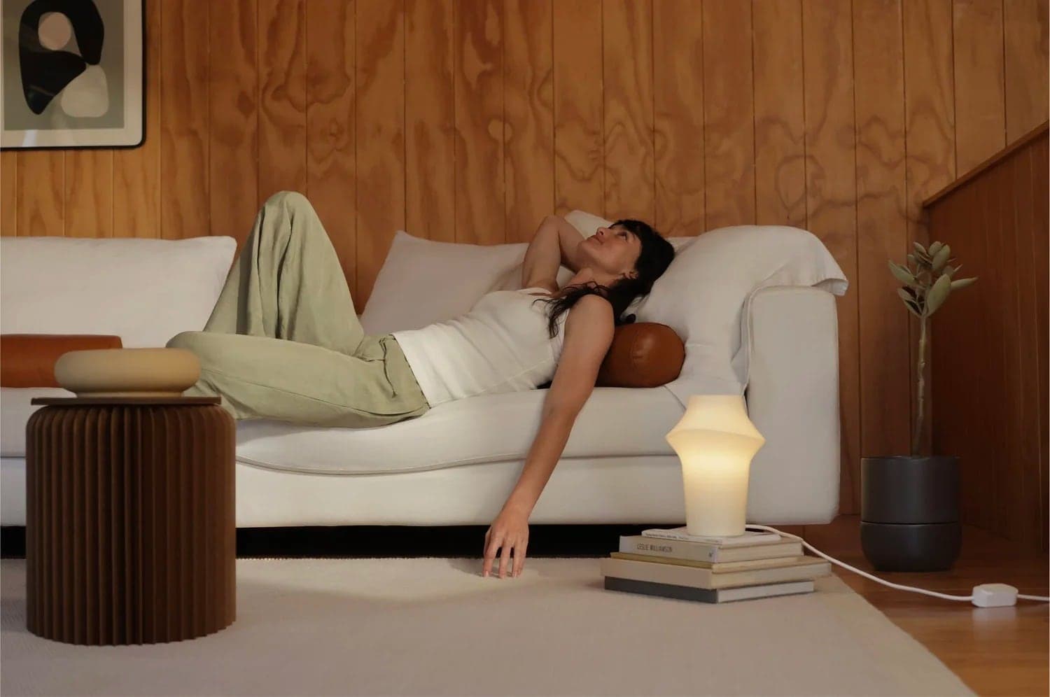Woman lounging on a white sofa beside a Fable lamp