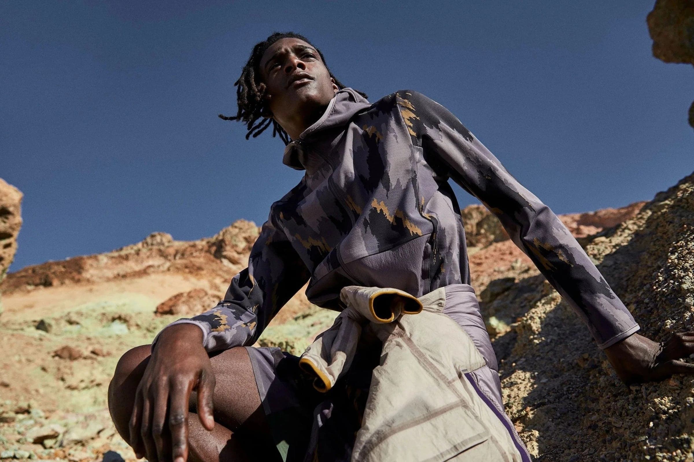Model in a camo jacket sitting on rocks