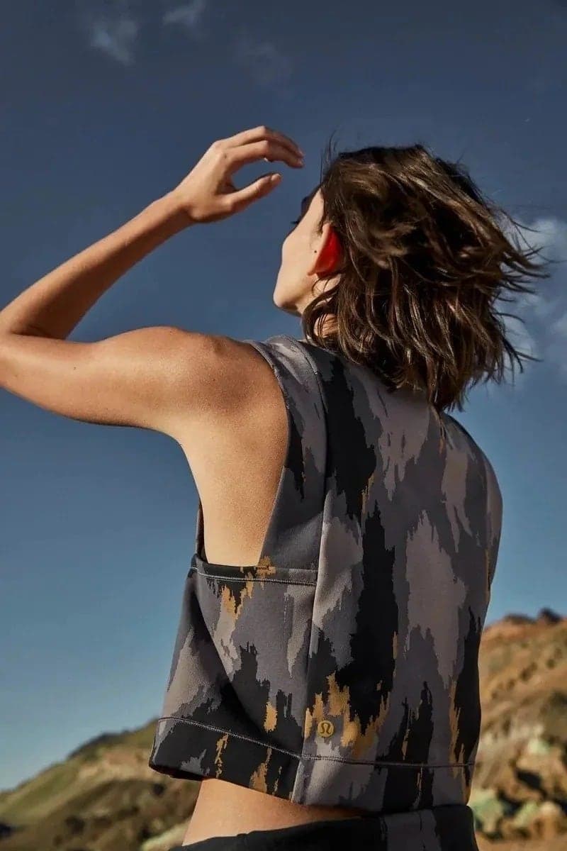 Model in a camo top shading her eyes against the sky