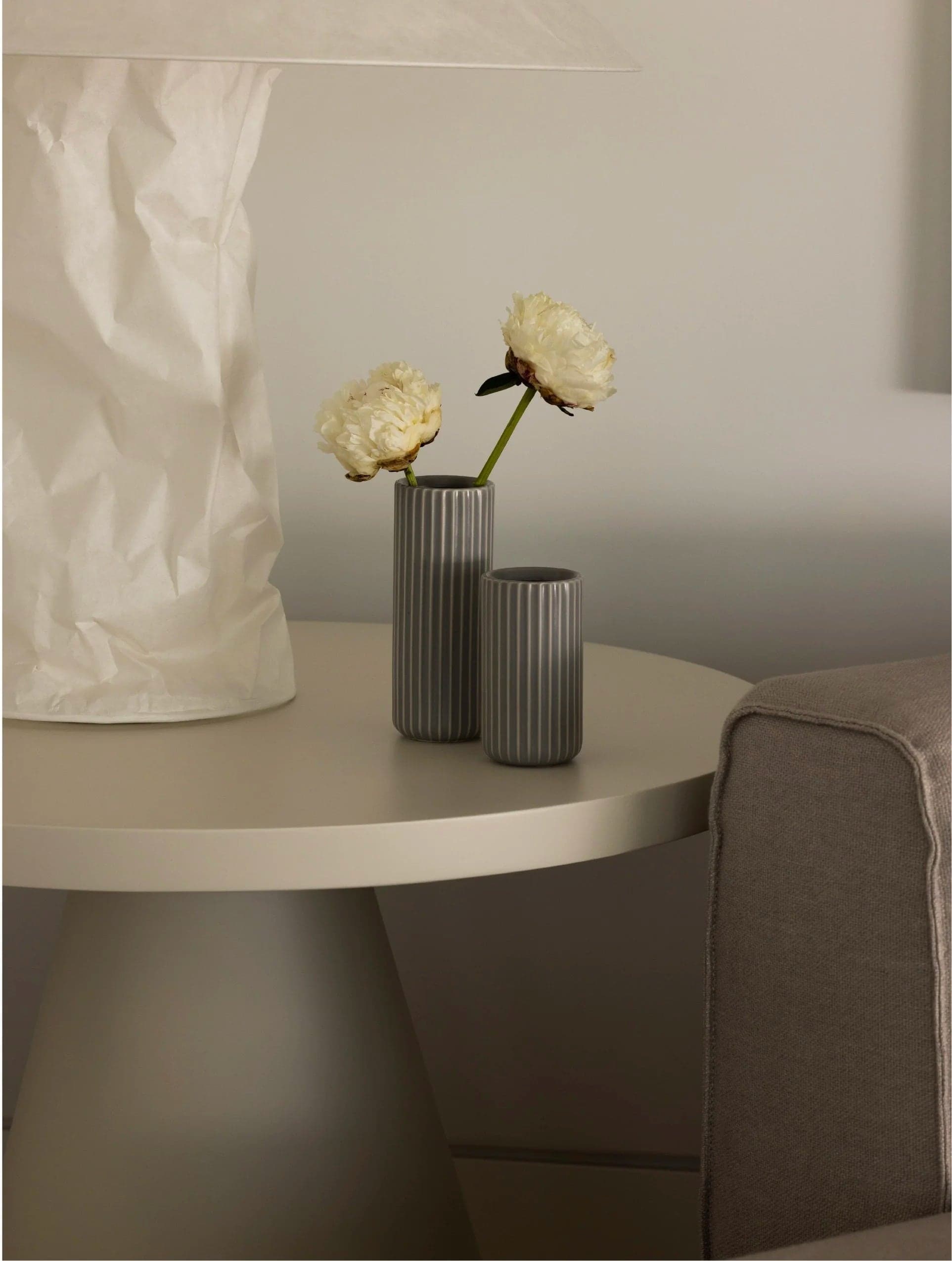 Two ribbed vases with roses on a side table