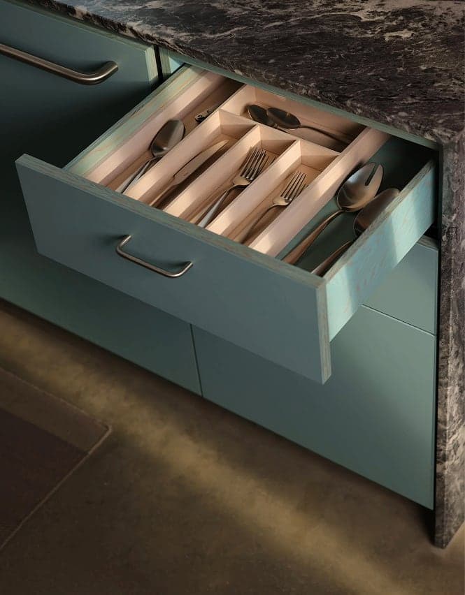 Open drawer of cutlery in blue cabinetry