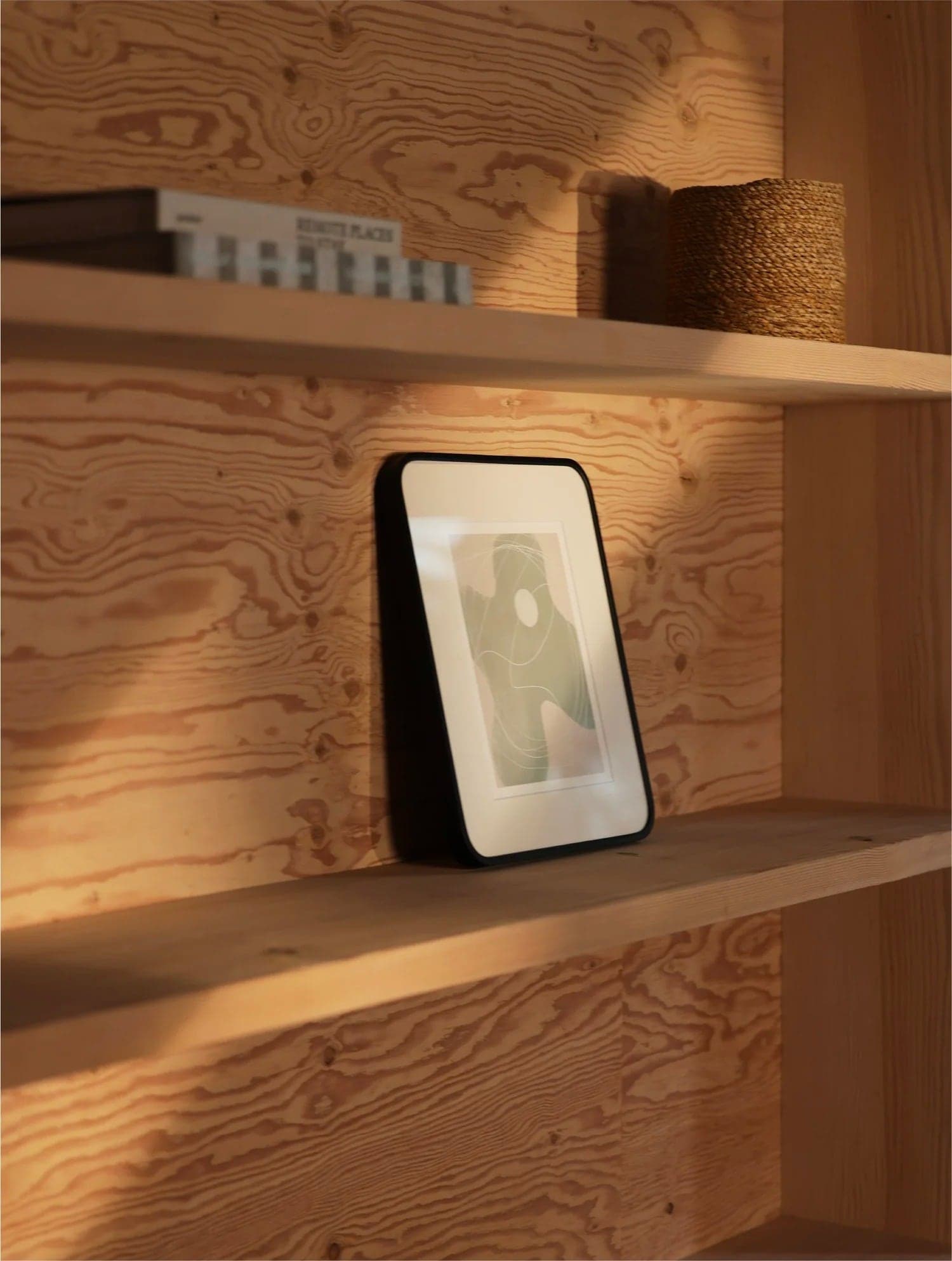 Framed print on a sunlit plywood shelf